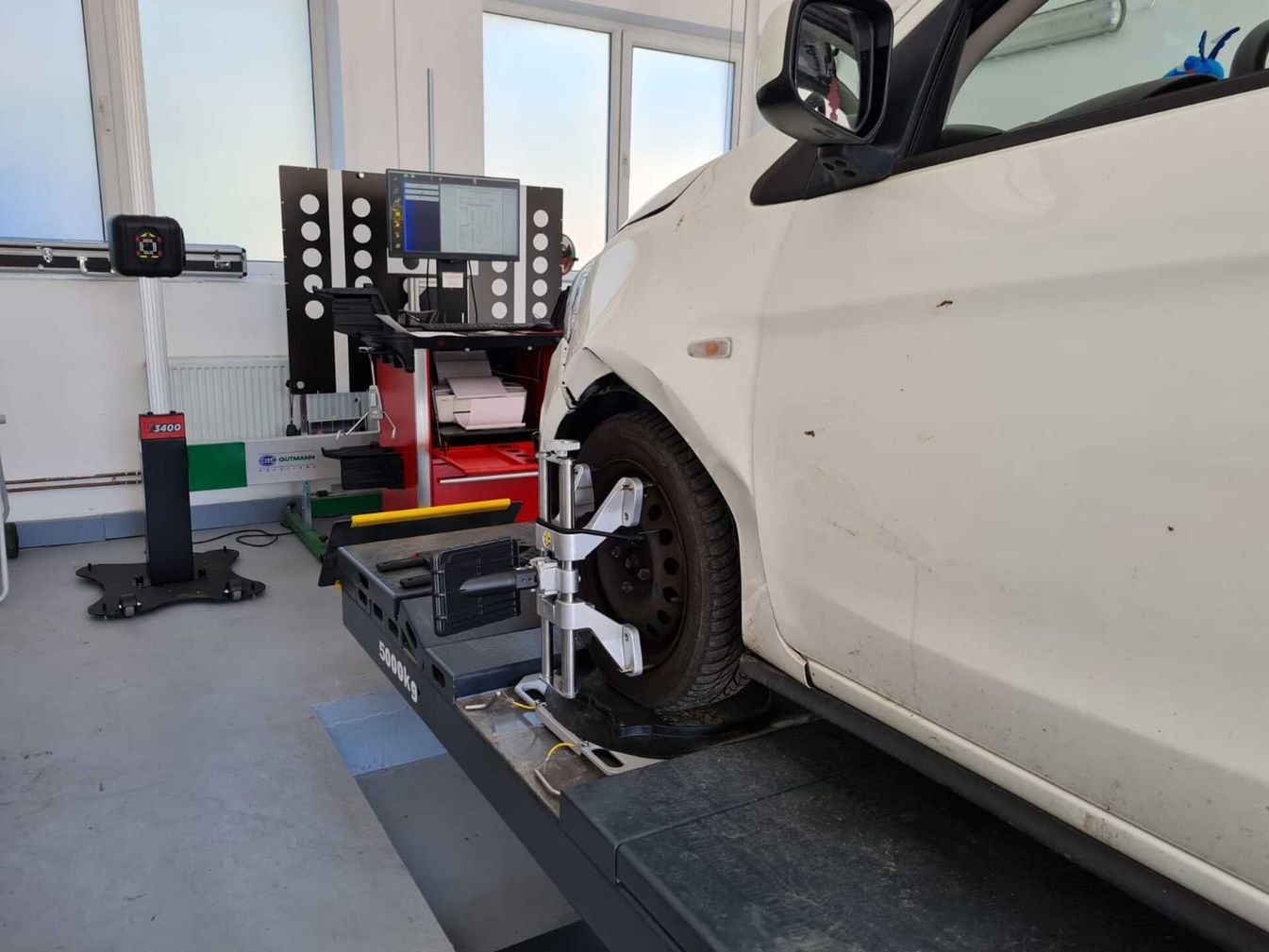 Die Achsvermessung an einem weißen Auto in unserer Werkstatt